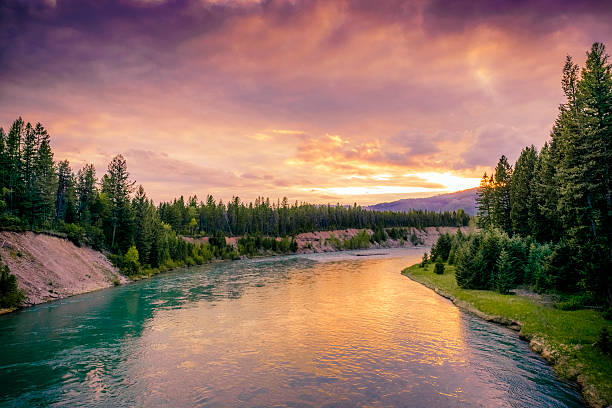 Colorful Montana Sunset in Glacier National Park Over River Scene This is a horizontal, color photograph of the scenic landscape of Glacier National Park at sunset. The Middle Fork Flathead River reflects the vibrant colors in the sky. The river banks are full of green conifer trees. Photographed in spring with a Nikon D800 DSLR camera. montana western usa photos stock pictures, royalty-free photos & images