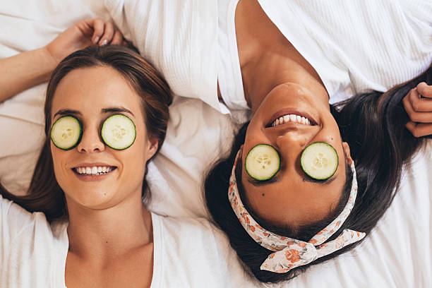 It's like a sleepover that never ends... Shot of two girlfriends relaxing with cucumber slices on their eyes cucumber slice stock pictures, royalty-free photos & images