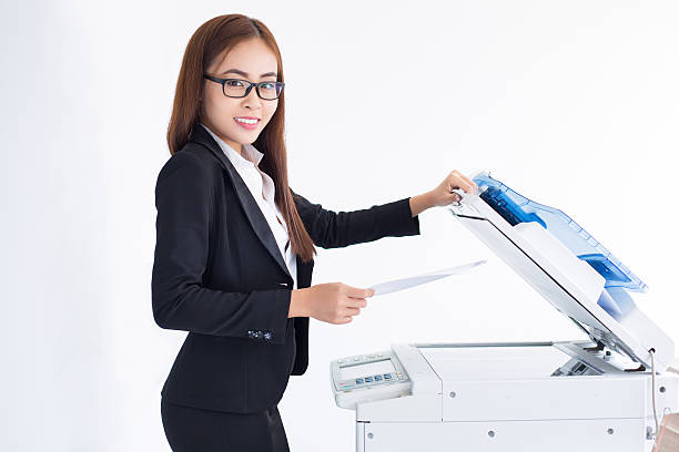 istock Smiling Asian Business Woman Using Copier Machine 635949342