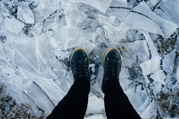 istock Male legs in leather boots standing on cracked ice 635953020