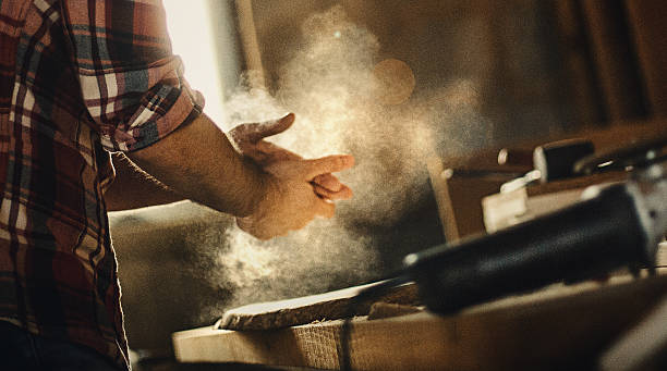 The job is done. Closeup of unrecognizable man dusting off his hands after finished job at a workshop. Backlit. craftsperson stock pictures, royalty-free photos & images