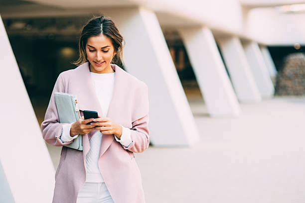 hermosa mujer elegante enviando mensajes de texto en el teléfono - contemporary elegance telephone urban scene fotografías e imágenes de stock