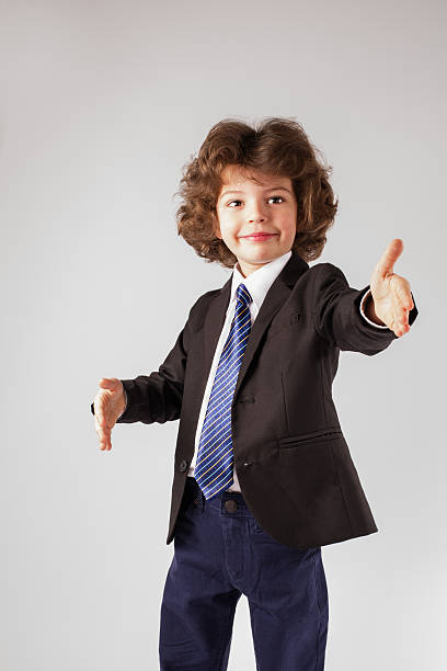 istock Curly happy boy stands, raised his hands. Gray background. 635957918