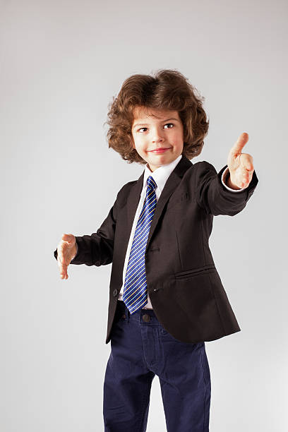 istock Curly boy stands, raised his hands. Gray background. 635958230