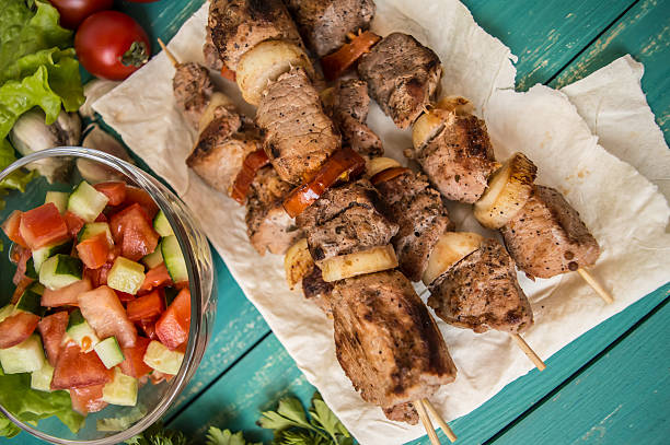 istock Pork cooked with vegetables on skewers  a turquoise table. Wooden 635959740