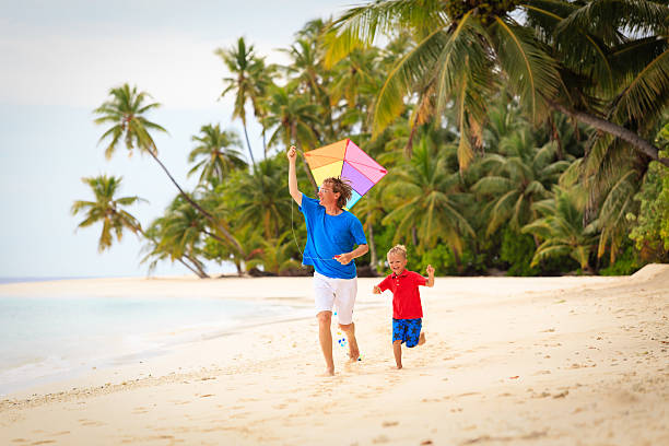 istock father and little son flying kite on beach 635961564