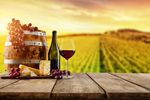 istock Red wine served on wooden planks, vineyard on background 635964296