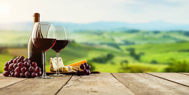 istock Red wine served on wooden planks, vineyard on background 635964332