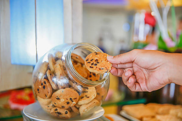 mani dei maschi che prendono il biscotto al cioccolato dal barattolo - biscotti cookie morning temptation foto e immagini stock