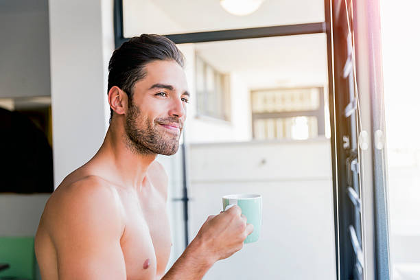 przemyślany młody człowiek trzymający filiżankę kawy w domu - shirtless caucasian freshness relaxation zdjęcia i obrazy z banku zdjęć