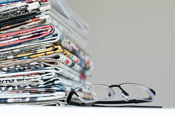 istock Newspapers with eyeglasses on white background 635969818