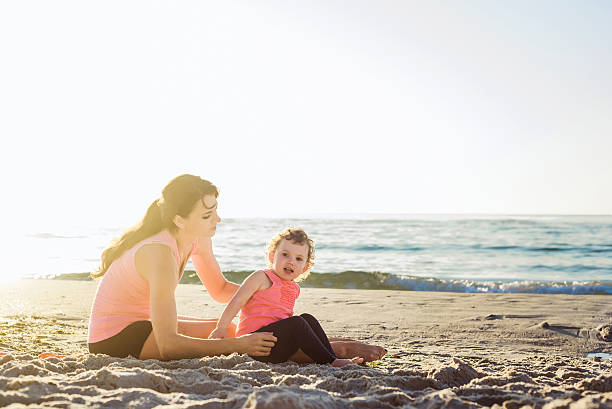 istock family workout - mother and daughter doing exercises on beach 635972574