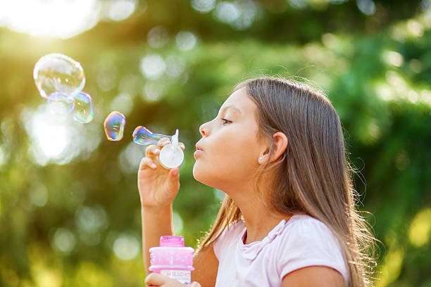 istock Children girl blowing soap bubbles outdoor 635972726