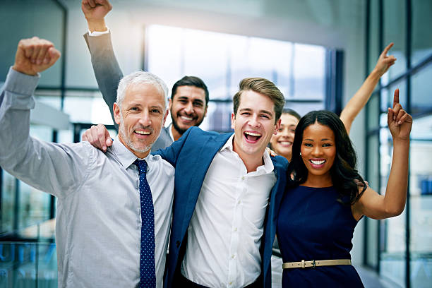 Success has been a well-earned win for them Portrait of a group of colleagues cheering together in an office cheering group of people success looking at camera stock pictures, royalty-free photos & images