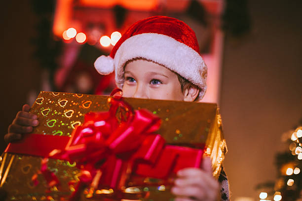 istock Little Boy in Santa Hat Holding Christmas Present 635977436
