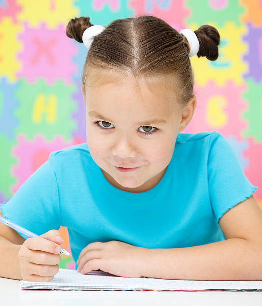 istock Little girl is writing using a pen 635977970
