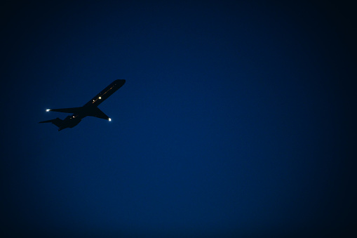 A silhouette of an airplane taking off in the night sky.