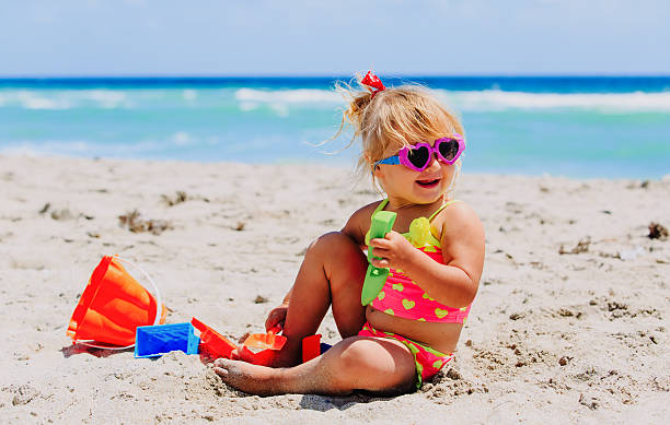 istock cute little girl play with sand on beach 635983946