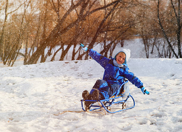 istock happy little boy on sledge in winter snow 635986890