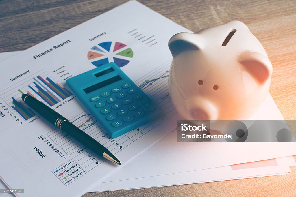 Piggy bank with business stuff. Piggy bank with business stuff, business and finance concept, vintage color tone. Finance Stock Photo