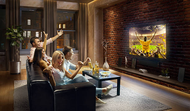 istock Couples cheering and watching sports game on TV 635987236
