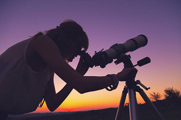 istock Girl looking at the stars through a telescope. 635988086