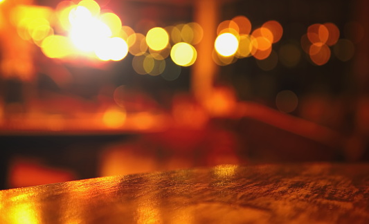 blur top of wood table at pub with bokeh light in the dark night background