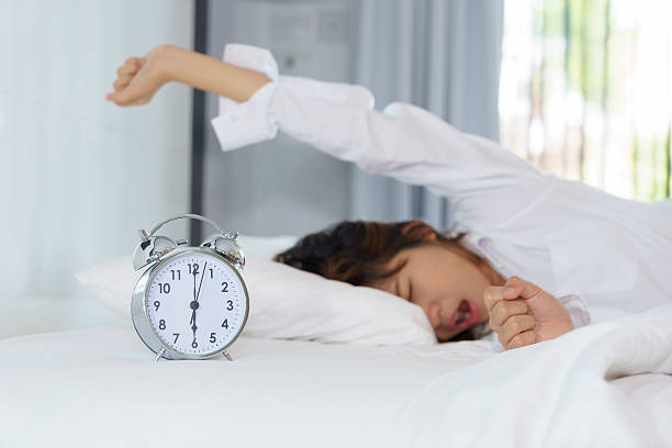 Woman stretching and yawning while waking up in the morning stock photo