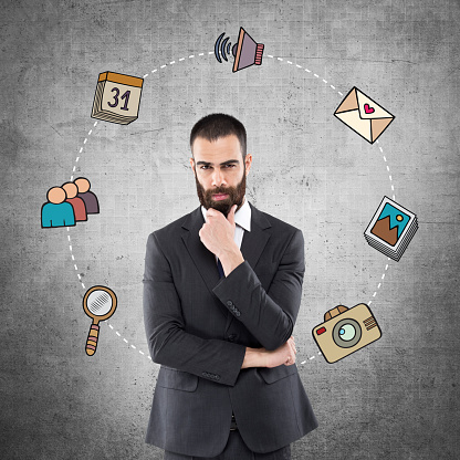 Portrait of young businessman with mobile app icons on wall