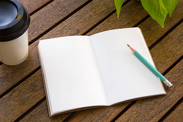 istock Notebooks, pencils, coffee cups on a wooden table 635999150