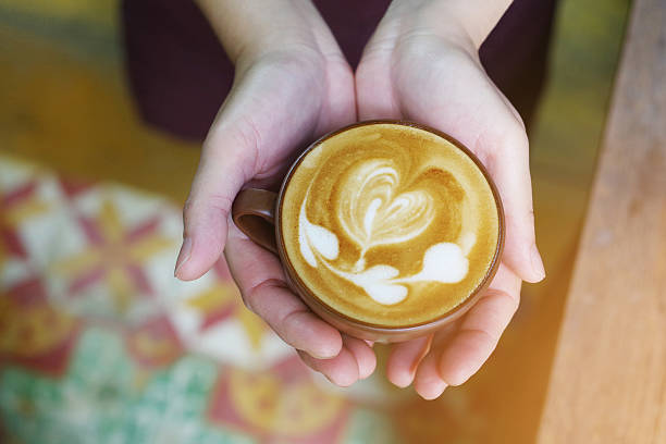 istock Top view of hands holding hot coffee latte cup 636000454