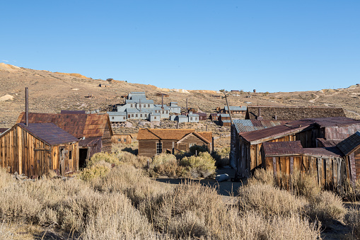 Photo shows an old wood house in Southern Alberta, Canada.  It has a covered porch and there is trash piled up around and in it.  Built in the early 1900’s and abandoned for decades, there is extensive wear showing to the wood and metal.  This house was built for settlers who moved up from the United States.  It was torn down in 2008 to make room for an expanded highway.