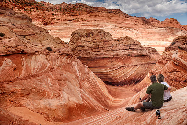 Amazed by the Wave A male tourist hugs his female companion as they overlook the spectacular sandstone rock formations known as the Wave located within the Paria Canyon-Vermilion Cliffs Wilderness, Page, Arizona, US, North America page arizona stock pictures, royalty-free photos & images