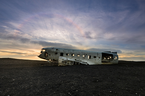 Amazing Solar halo over crashed DC-3 Airplane on Solheimasandur beach at sunset. Airplane wreckage on black sand beach in South Iceland.