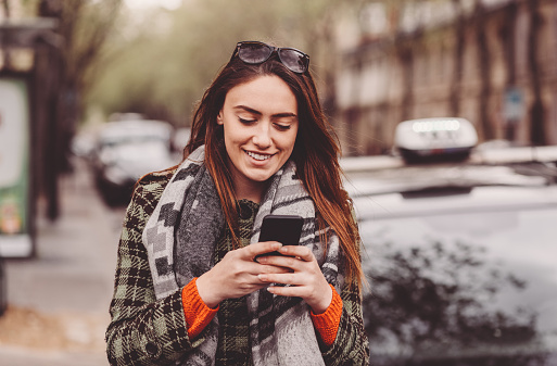 Smiling woman texting at the street