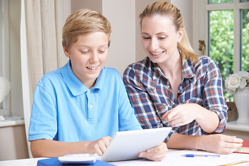 Female Home Tutor Helping Boy With Studies Using Digital Tablet