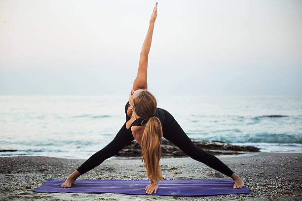 istock young caucasian female practicing yoga on beach 636011370