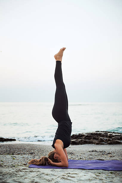 istock young caucasian female practicing yoga on beach 636011722
