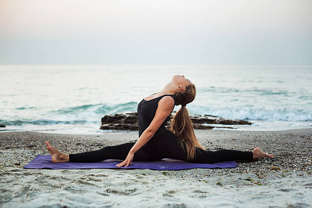 istock young caucasian female practicing yoga on beach 636011832