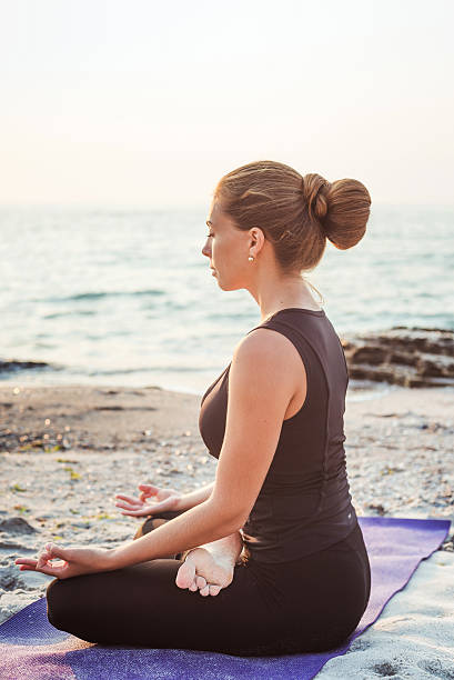 istock young caucasian female practicing yoga on beach 636012640