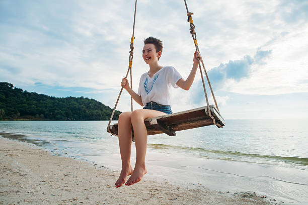 istock Happy girl on a swing tropical island 636014628