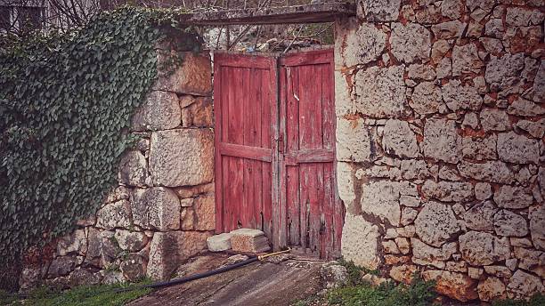 istock Old Stone Building Facade Painted Peeling European Red Barn Door 636018892