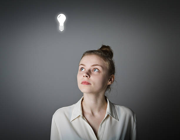 girl and light bulb - unintelligent imagens e fotografias de stock