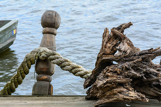 Rope knotted along a ship bollard. Docks with rope in harbor, blue background and boat fragment.