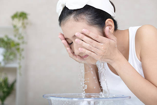 woman washing her face - gezicht wassen stockfoto's en -beelden