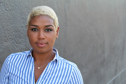 Beautiful young African American woman with short dyed blond hair looking at camera with a relaxed neutral expression.