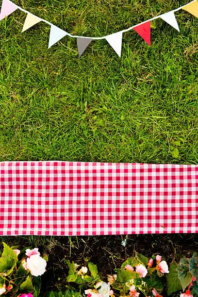 A composition of summer ingredients; grass, pennants, flowers and blankets.