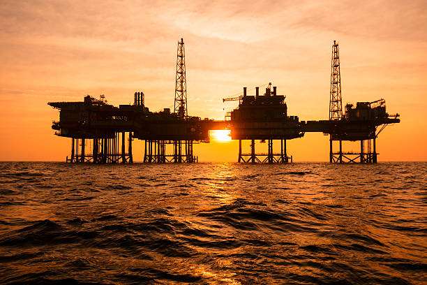 silhouette of an offshore oil installation - derrick crane drilling rig well sky imagens e fotografias de stock