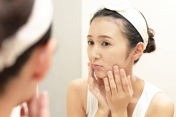 Young woman having skin problems Asian woman looking at her face in mirror kyushu photos stock pictures, royalty-free photos & images