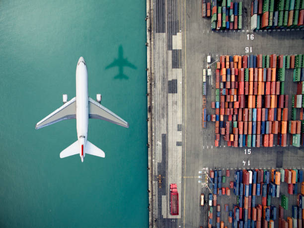 airplane flying over container port - container ship stockfoto's en -beelden